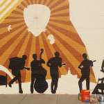 Custom mural being painted on the face of the Elderly Instruments building in Lansing, MI