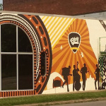 Custom mural being painted on the face of the Elderly Instruments building in Lansing, MI