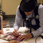 Hall of Fame member Jesse McReynolds signing Hall of Fame book at Wide Open Bluegrass 2016 - photo © Tara Linhardt